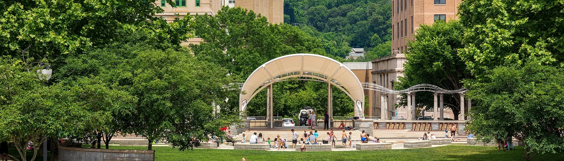 Niños jugando en el parque del centro de Asheville, Carolina del Norte, mientras los adultos montan en bicicleta o pasean por la escena.