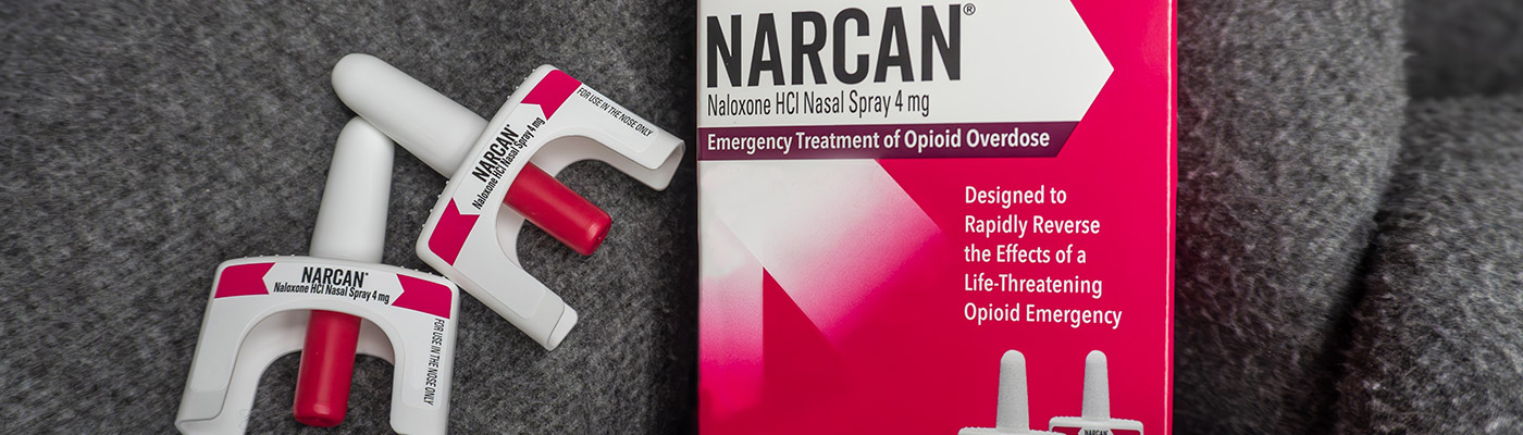 Una caja de NARCAN y dos inhaladores sobre una manta gris.