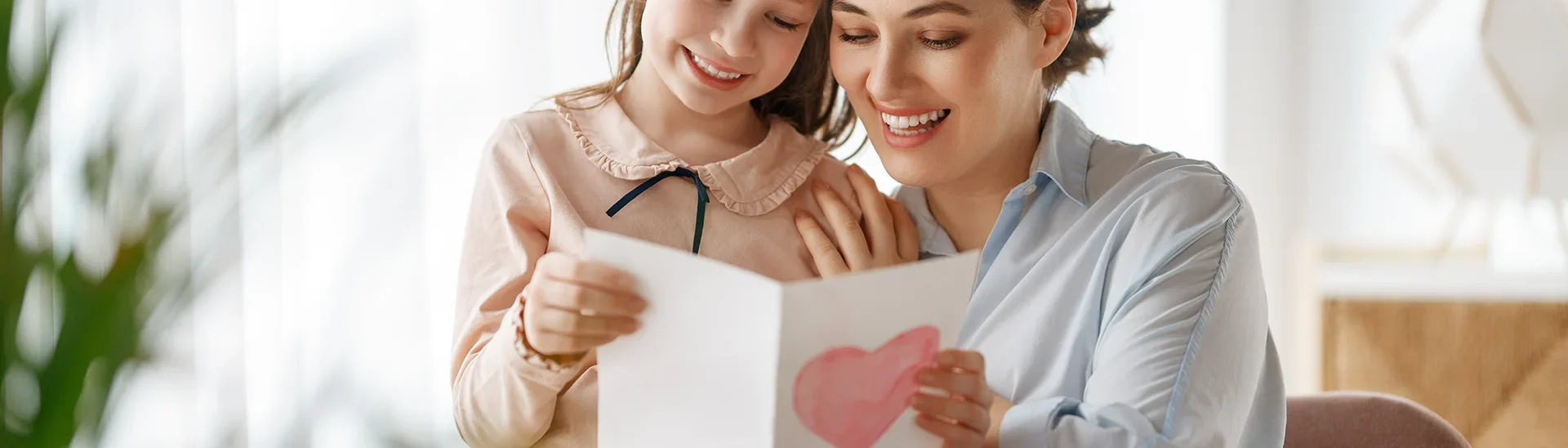 Mother and her daughter sharing a card with a drawn heart on the front.