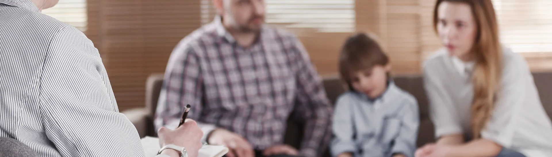 Female therapist listening to a child talking about his feelings while is mother and father site on either side of him.