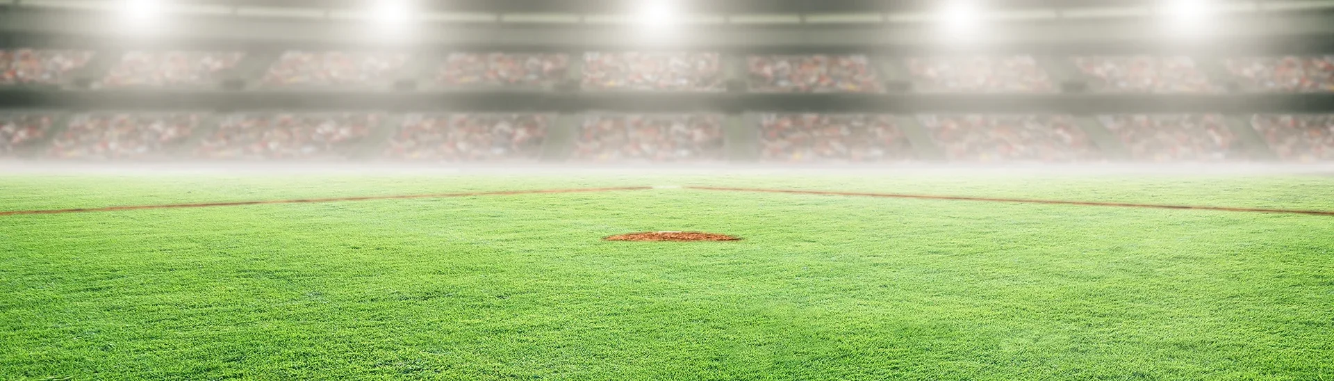 Campo de béisbol de hierba iluminado por la noche.