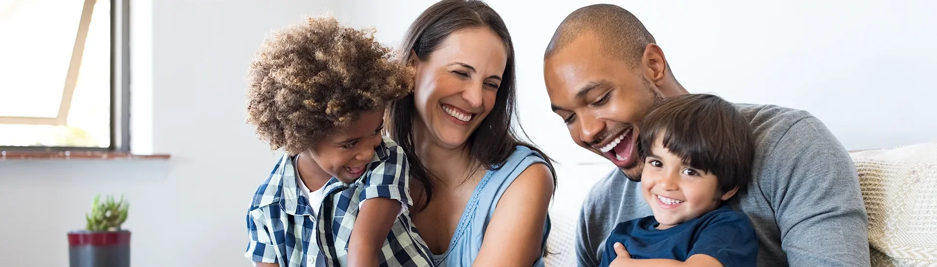 Familia diversa sentada en el sofá riendo juntos.