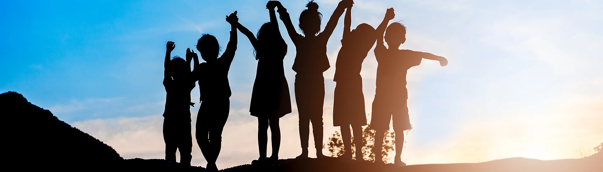 Silhouette of a group of kids holding hands and celebrating