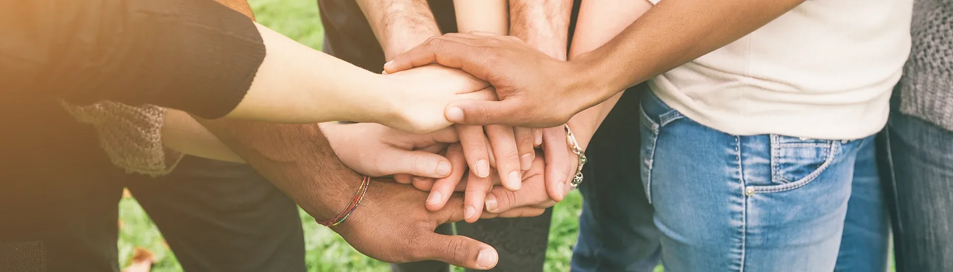 Several people of different ethnicities standing in a circle with their hands on top of each others.